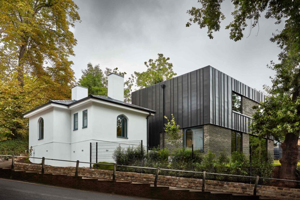 Restored white gatehouse beside the dark-clad extension at Little Lodge
