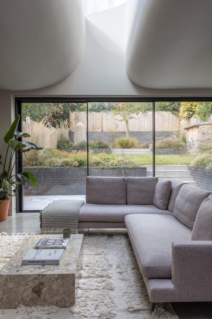 Living room with a glazed wall opening onto the garden at Heavy and Light House
